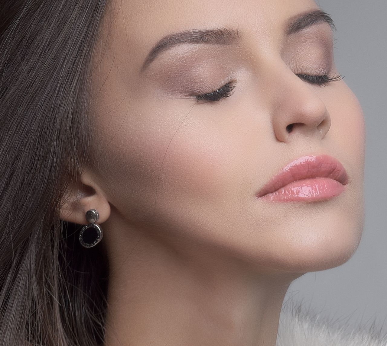 about-us-02 Close-up portrait of a woman with closed eyes, focusing on soft makeup and delicate features.