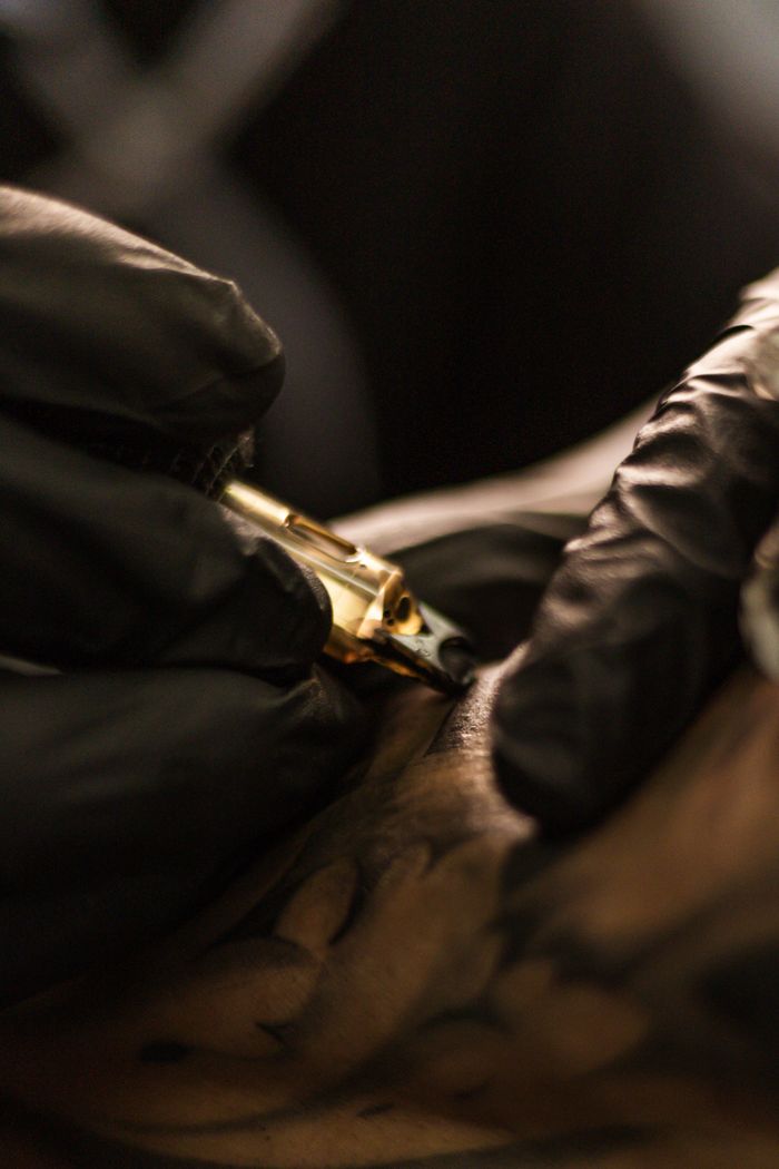 how-it-works Detailed view of a tattoo artist using tattoo machine on skin, showcasing precision and skill.