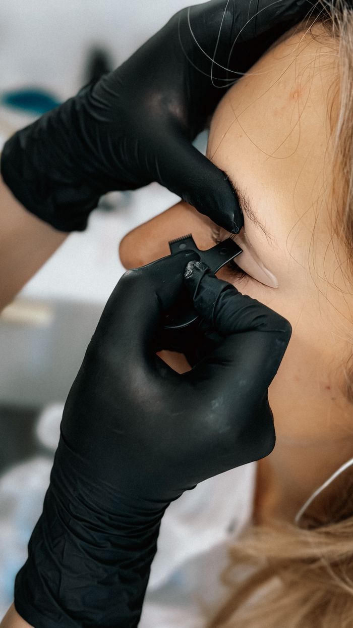 services-01 Close-up of a person receiving an eyebrow tattoo by a professional artist wearing gloves.