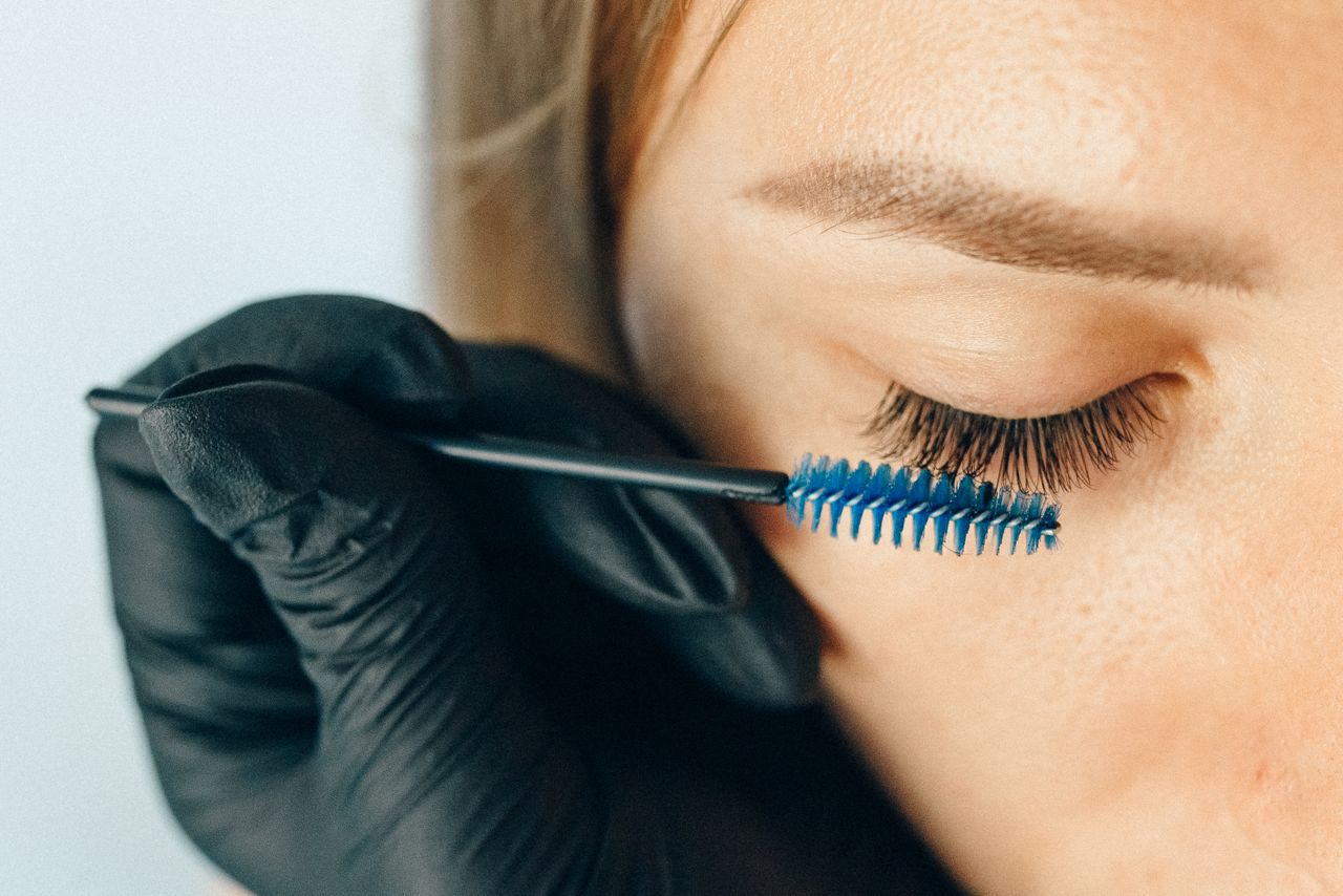 services-03 A professional applying eyelash extensions using a blue applicator brush for a refined look.