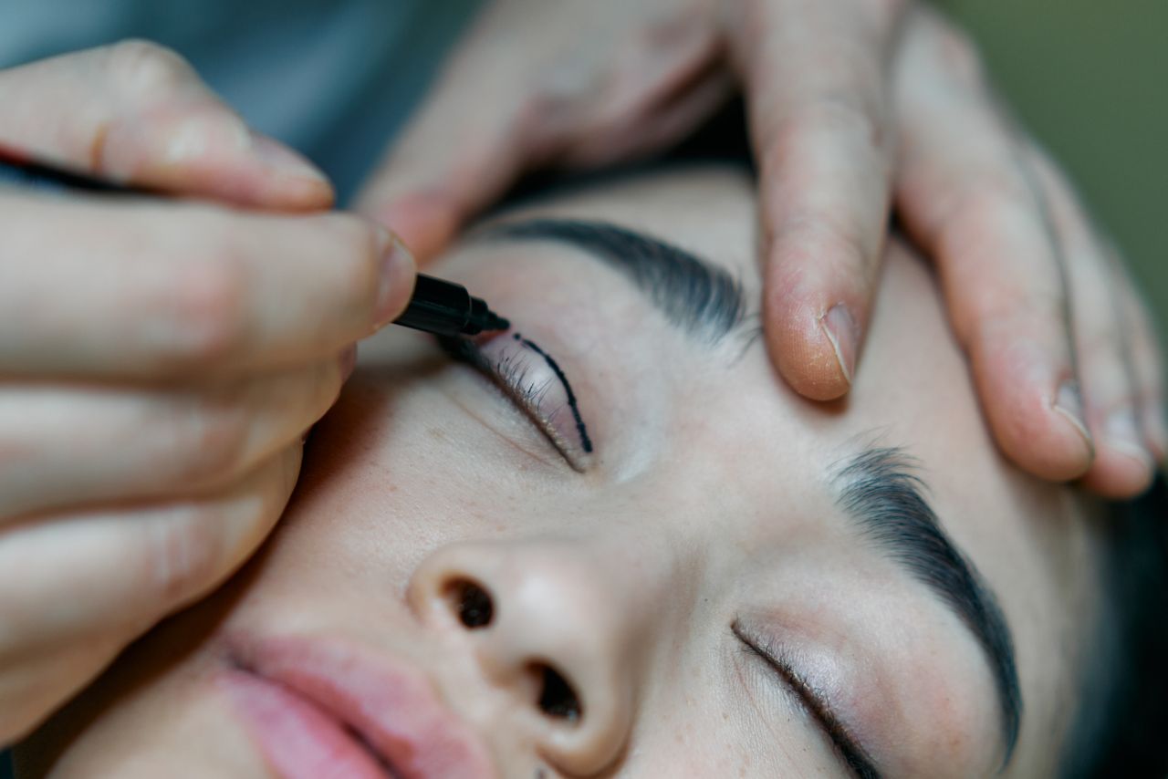 services-02 A close-up image of a makeup artist applying eyeliner to a woman's eyelid with precision.