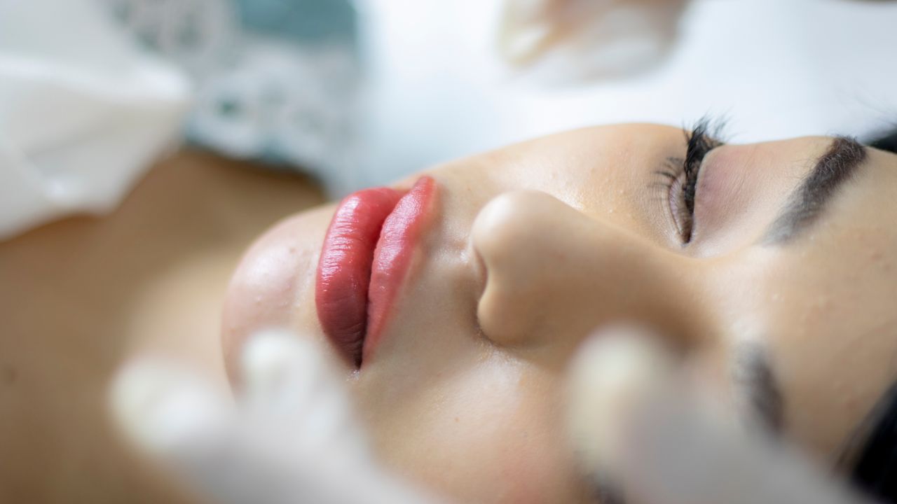 about-us-01 Close-up shot of a woman receiving a skincare treatment, highlighting red lipstick and eyelashes.